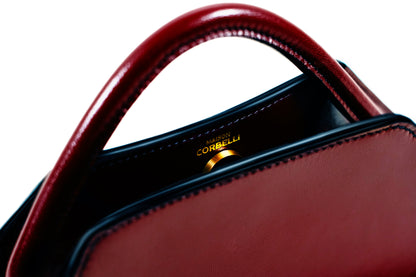 Elie mini bag, Model, Studio, Burgundy, Clutch bag, Hand bag, mediterranean vibe, Premium leather, Unique design, Maison Corbelli, Luxury, Close up, white background