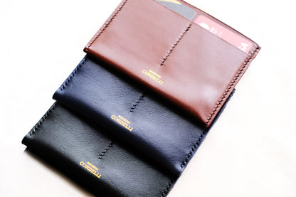 Three leather wallets, one black and one Navy blue and one cognac, with "maison Corbelli" branding  in gold on a white background, Pure leather, Photo studio 