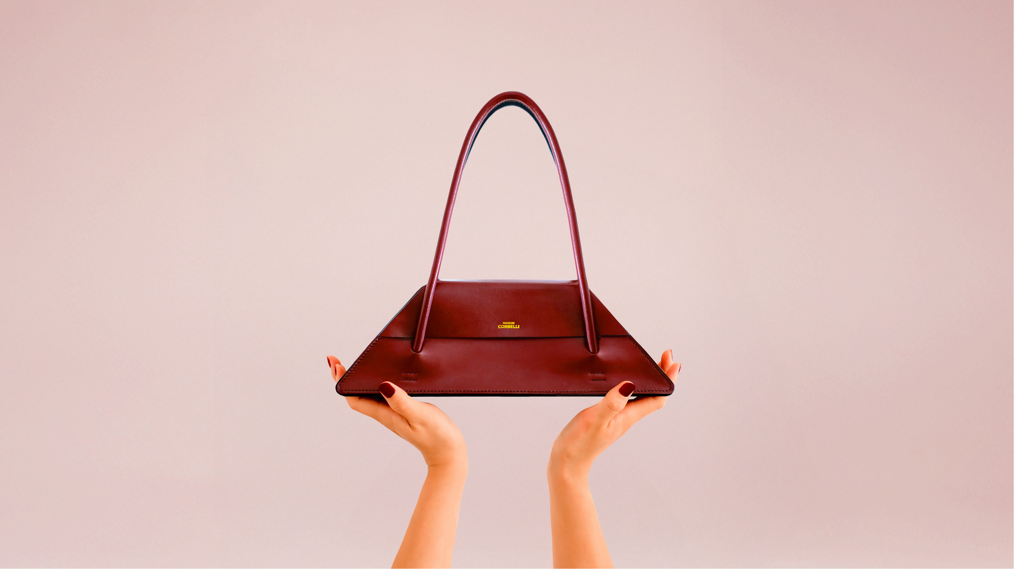 Elie bag by Maison Corbelli — a handcrafted burgundy handbag made from Italian calf leather, featuring an architectural silhouette, minimalist lines, and Parisian-inspired elegance. Each piece is shaped by hand with meticulous craftsmanship, reflecting the timeless aesthetic of Maison Corbelli.